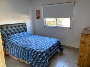 ein Schlafzimmer mit einem Bett mit blauer Decke und einem Fenster in der Unterkunft Los Talares in Baradero