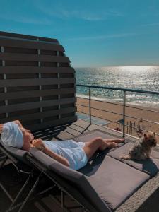 a woman laying on a chaise lounge next to a dog at Apart-Hotel Poseidon in Odesa