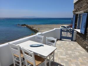 uma mesa branca e cadeiras numa varanda com vista para o oceano em Anthie's shore house em Istérnia