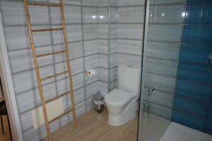 a bathroom with a toilet and a glass shower door at Apartamento Azul in Quarteira +2 photos