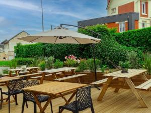 eine Gruppe Picknicktische mit einem Sonnenschirm auf einem Deck in der Unterkunft Hotel Ibis Budget Fecamp in Fécamp