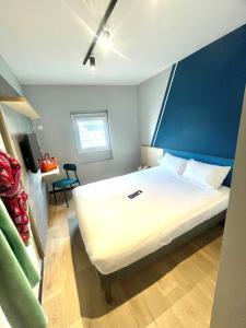 ein Schlafzimmer mit einem großen weißen Bett und einer blauen Wand in der Unterkunft Hotel Ibis Budget Fecamp in Fécamp