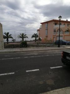 una calle con un edificio y palmeras en el fondo en vista al mar. en Caleta de Interián