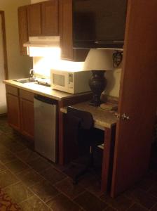 a kitchen with a microwave and a table with a lamp at L'Acadie Inn & RV Park in Eunice
