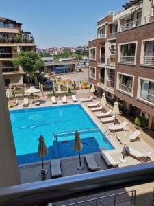 a view of a swimming pool with chairs and umbrellas at Апартамент Весела-Хоризонт in Sozopol