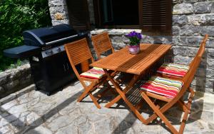 a wooden table and two chairs next to a grill at Villa Dobra in Plitvička Jezera
