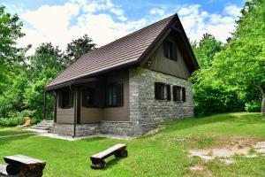 una pequeña casa con dos bancos delante en Villa Dobra, en Lagos de Plitvice