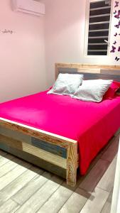 德賽的住宿－BUNG À ZIOTTE，一张带粉红色床单和木架的床
