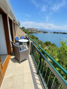 een balkon met een tafel en stoelen en uitzicht op het water bij Kommeno Bay Apartments in Corfu-stad