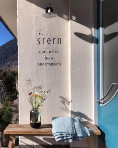 Stern B&B & Suite Apartments في نوفا ليفانتي: إناء من الزهور على طاولة خشبية