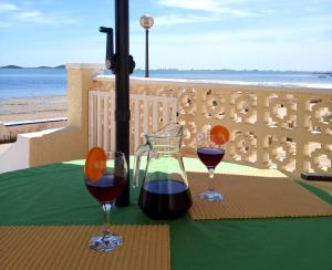 two glasses of wine on a table with a view of the beach at Beachfront House sea views near historic Cartagena in Cartagena