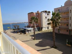uma varanda com palmeiras em frente a um edifício em Joli appartement avec grande et belle terrasse, au pied de la plage du Grazel! em Gruissan