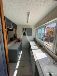 uma grande cozinha com um lavatório e uma janela em Joli appartement avec grande et belle terrasse, au pied de la plage du Grazel! em Gruissan