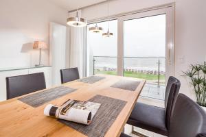 un tavolo da pranzo con sedie e una grande finestra di Penthaus 14 Strandvilla Therese a Norderney Altre 9 foto