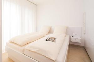 un letto con lenzuola bianche e un libro sopra di Penthaus 14 Strandvilla Therese a Norderney