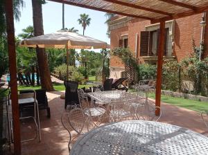 a patio with tables and chairs and an umbrella at Villa dei Marchesi Carrozza in Santa Teresa di Riva