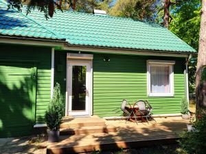 a green house with a bench on the porch of it at G3 in Palanga