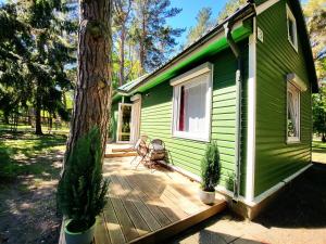 a green house with a wooden deck next to a tree at G3 in Palanga