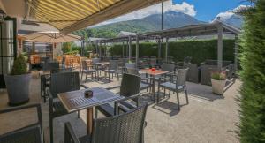 eine Außenterrasse mit Tischen, Stühlen und Sonnenschirmen in der Unterkunft Hôtel Aurélia in Saint-Lary-Soulan