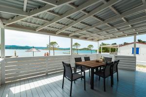 圖納的住宿－Adria Nova kamp Laguna，甲板上的木桌和椅子,享有水景