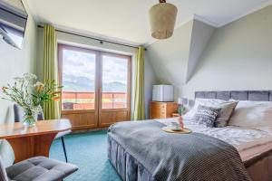Schlafzimmer mit einem Bett, einem Tisch und einem Fenster in der Unterkunft Pokoje i apartament z widokiem na Tatry in Kościelisko