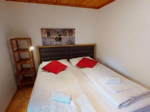 ein großes weißes Bett mit zwei roten Kissen darauf in der Unterkunft Chalet Fürth - by Four Seasons Apartments in Piesendorf