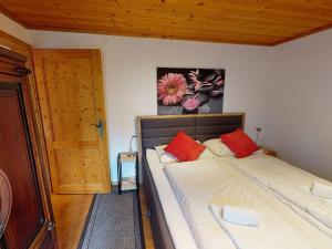 ein Bett mit zwei roten Kissen in einem Zimmer in der Unterkunft Chalet Fürth - by Four Seasons Apartments in Piesendorf