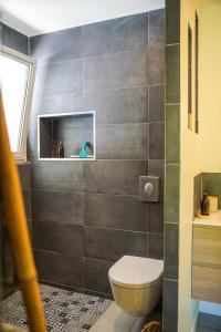 a bathroom with a toilet and a tile wall at suite indépendante au calme avec piscine in Aix-en-Provence