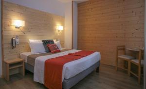 1 dormitorio con 1 cama y 1 mesa con teléfono en Hôtel Aurélia en Saint-Lary-Soulan