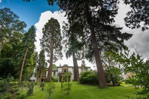 a house in the middle of a yard with trees at Macdonald Norwood Hall Hotel in Aberdeen