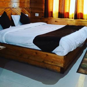 a large wooden bed with white sheets and pillows at Hotel Himalayan Galaxy in Chakrāta