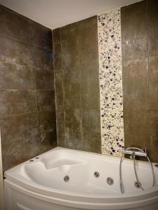 uma banheira branca numa casa de banho com azulejos em Forever Friday Apartment Cosmopolis em Creţuleasca