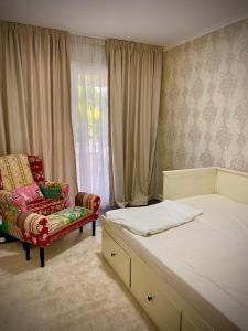 um quarto com uma cama, uma cadeira e uma janela em Forever Friday Apartment Cosmopolis em Creţuleasca