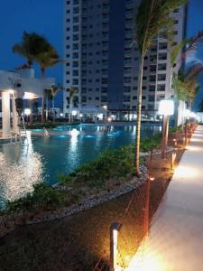 a swimming pool at night with palm trees and a building at Salinas Exclusive Resort in Salinópolis