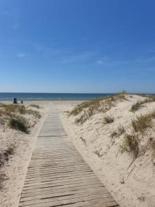 einen Holzweg durch den Sand am Strand in der Unterkunft Pie jūras in Liepāja