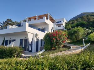 a white house on a hill with flowers at Kapetaniou Apartments in Limnionas