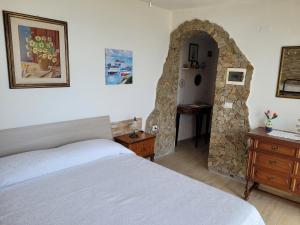 1 dormitorio con cama y pared de piedra en Villetta con piscina panoramica Belvedere Mari Pintau, en Geremèas