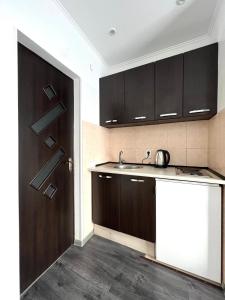 a kitchen with dark wood cabinets and a sink at Комфортні апартаменти 82 in Ivano-Frankivsʼk