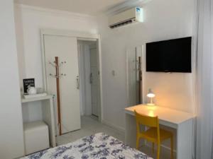 a bedroom with a bed and a table and a desk at Village pé na areia com limpeza in Lauro de Freitas