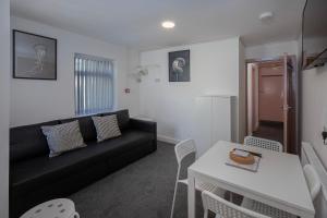 sala de estar con sofá negro y mesa en Jellyfish Apartments en Blackpool