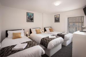 Tres camas en una habitación con paredes blancas. en Jellyfish Apartments, en Blackpool