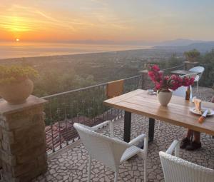 uma mesa e cadeiras numa varanda com o pôr-do-sol em La Pastorella em Maierà