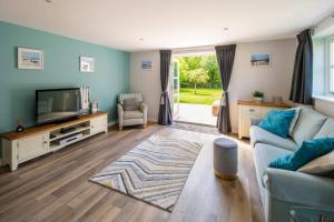 a living room with a couch and a tv at Osbornes Holiday House near Exeter with swimming pool in Exeter