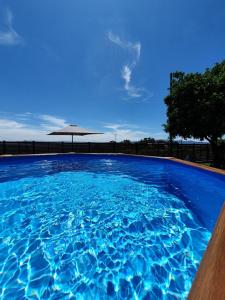 una gran piscina azul con sombrilla en Rosinha Country House en Vale de Cambra