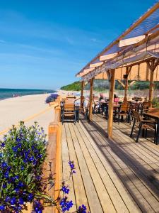 a wooden deck with tables and chairs on the beach at Sunny Apartament in Pustkowo