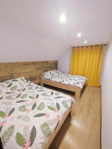 2 Betten in einem Zimmer mit gelben Vorhängen in der Unterkunft Poddasze ceglane - Warpuny-Mazury- 12 km od Mrągowa in Warpuny