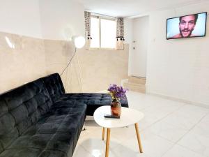 Una sala de estar con un sofá negro y una mesa. en Estudios GLORIA, en Alicante