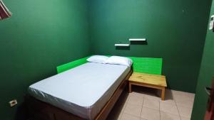 a small green room with a bed and a wooden table at OYO 91341 D'phoenix Anggrek Syariah Residence in Jakarta