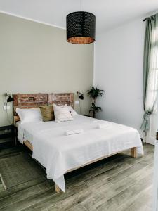 a white bedroom with a large bed with white sheets at The Olive Grove in Tuscany in Toiano