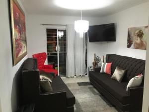 Hato MayorNew Condo Palma Real 3 bd Apt 5 mins from STi的客厅配有黑色沙发和红色椅子